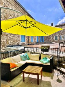 a large yellow umbrella on a balcony with a couch at Les Voyageurs in Charols