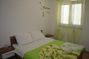 una camera da letto con un letto con una coperta verde e una finestra di Apartments Mare a Baška