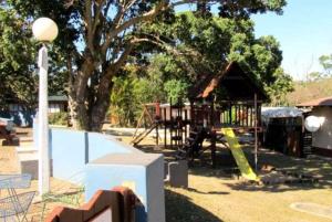 a playground in a park with a tree and a building at Nature's Cottage in Hibberdene