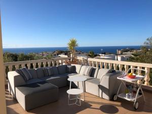 d'une terrasse avec un canapé et des tables sur un balcon. dans l'établissement Lirios Boutique Luxury Seaview Villa, à Benitachell