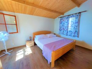 a bedroom with a bed and a window and a fan at Vala Hrvaska Robinson in Gornji Humac