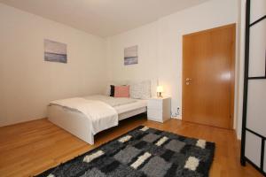a white bedroom with a bed and a rug at Steira-Studios Leibnitz in Leibnitz