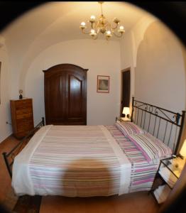 una camera con un grande letto e un lampadario a braccio di Casa Romeo ad Adrano