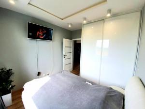 a bedroom with a bed and a tv on the wall at Apartament 40 in Iława