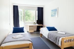 a bedroom with two beds and a desk and a window at ISLO Hostel in Joensuu