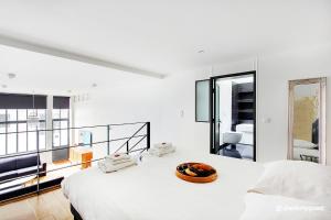 a white bedroom with two beds and a balcony at CMG Faubourg Saint-Martin in Paris