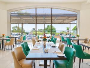a dining room with tables and chairs and a large window at St Raphael Resort in Limassol