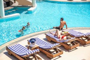 a group of people sitting on lounge chairs in a swimming pool at St Raphael Resort in Limassol