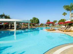 a large pool with chairs and umbrellas at a resort at St Raphael Resort in Limassol