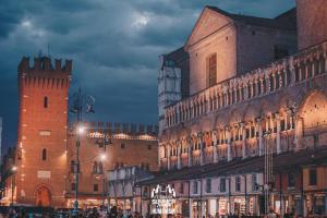 un edificio con una torre dell'orologio in una città di notte di Be Happy a Ferrara