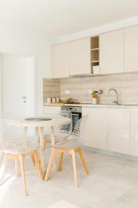 eine weiße Küche mit einem Tisch und Stühlen in der Unterkunft Apartmani Toma in Pakoštane