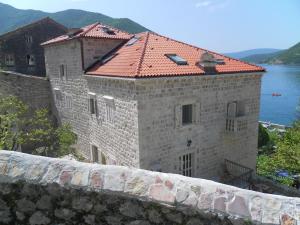 a large stone building with a red roof next to the water at Apartments David in Perast