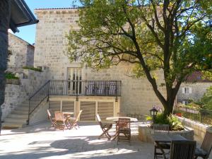 patio z krzesłami i stołem przed budynkiem w obiekcie Apartments David w mieście Perast