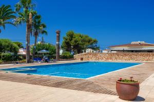 a swimming pool in a resort with palm trees at Sa Perdiu 30 in Cala Santandria