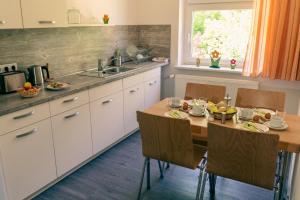 eine Küche mit einem Holztisch mit Stühlen und einem Waschbecken in der Unterkunft Gästehaus am Oberlausitzer Dreieck in Bertsdorf