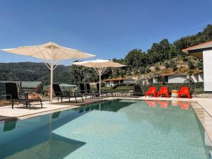 a swimming pool with chairs and umbrellas at Encosta de Louredo by Pousadela Village in Vieira do Minho