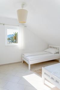 ein weißes Zimmer mit einem Bett und einem Fenster in der Unterkunft Seafront apartments in Tivat