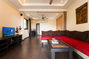 Koh Tao Heights Exclusive Apartments في كو تاو: غرفة معيشة مع أريكة حمراء وتلفزيون