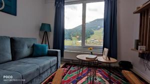 a living room with a couch and a large window at Apartman Snjezna pahuljica - FREE GARAGE in Bjelašnica