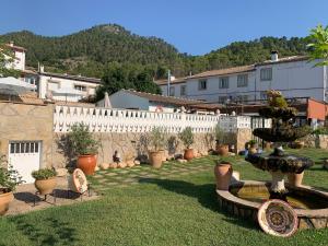 un jardín con una fuente y una valla blanca en Hotel Mirasierra, en Coto Ríos