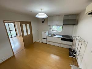 a kitchen with white cabinets and a wooden floor at Hotel Isodokei in Shirahama