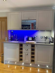 a kitchen with white cabinets and a blue wall at The Allanbreck Studio Glencoe in Glencoe