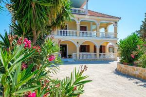 a large yellow house with palm trees and flowers at La MAISON di Angelo STUDIO in Ayios Kirikos
