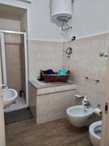 uma casa de banho com um lavatório, um WC e uma cesta. em La casa di sara em Nuoro