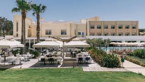 a restaurant with tables and umbrellas in front of a building at Mangia's Himera Resort in Campofelice di Roccella