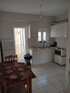 a kitchen with white cabinets and a table and a table and chairs at Ostria in Preveza