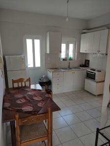 a kitchen with white cabinets and a table and chairs at Ostria in Preveza