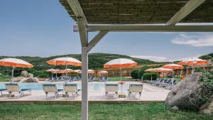 una piscina con mesas, sillas y sombrillas en MClub Marmorata en Santa Teresa Gallura