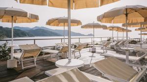 a deck with chairs and tables and umbrellas at Mangia's Pollina Resort in Cefalù