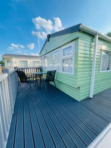 una casa verde con una mesa y sillas en una terraza en Lakeside Holiday Rentals - Delta, en Great Billing