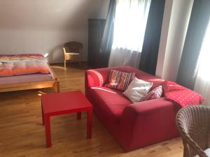 a living room with a red couch and a table at Ferien- und Messeappartement Schwaig in Schwaig bei Nürnberg