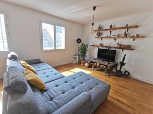sala de estar con sofá azul y TV en Le Globe-trotter - Les Maisons de Madeleine, en Nantes