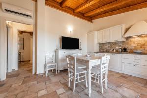 une cuisine avec des armoires blanches et une table et des chaises dans l'établissement Mattia House, à Villasimius