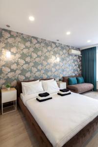 a bedroom with a large white bed with floral wallpaper at Alfa Apartments Svobody 39 in Lviv