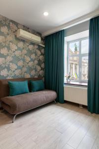 een woonkamer met een bank voor een raam bij Alfa Apartments Svobody 39 in Lviv