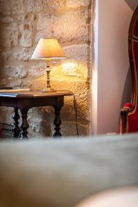 a lamp on a table in front of a stone wall at Hôtel La Couleuvrine Sarlat Centre Ville in Sarlat-la-Canéda