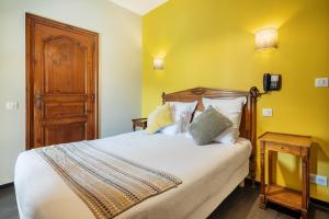 a bedroom with a large bed with yellow walls at Hôtel La Couleuvrine Sarlat Centre Ville in Sarlat-la-Canéda