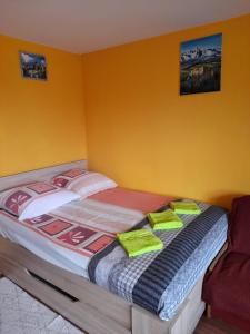 a bed in a room with yellow walls at Majkowiczówka in Czorsztyn