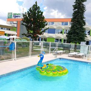 a man is swimming in a pool in a swimming pool at Holiday Inn Express Strasbourg - Sud, an IHG Hotel in Geispolsheim