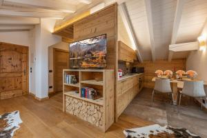 a kitchen and dining room with a table and a tv at Chalet Mountain Plaza - Apt Greenvalley in Pinzolo