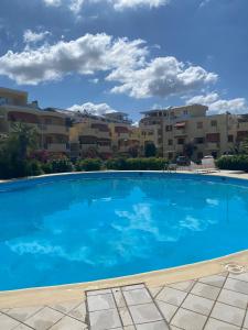 a large blue swimming pool in front of apartment buildings at Casada's House in Alghero