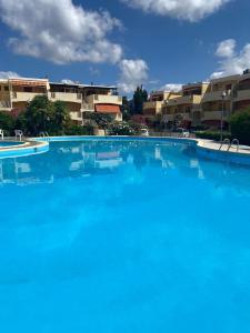 a large blue swimming pool with buildings in the background at Casada's House in Alghero