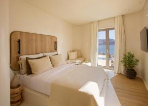 sypialnia z dużym białym łóżkiem i oknem w obiekcie White Pebble Suites w mieście Pollonia