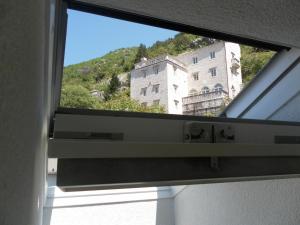 a window with a view of a building at Apartments David in Perast