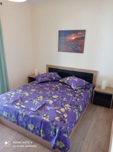 a bedroom with a bed with a purple comforter at Sunset Apartment in Epanomi