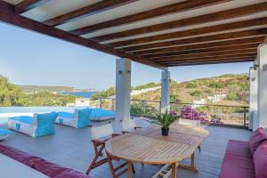 un patio con mesa y sillas y vistas al océano en Cape Sounio Villa, en Sounio